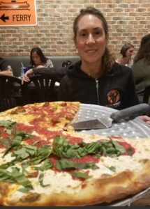 A woman eating pizza at a restaurant in East Brunswick, NJ