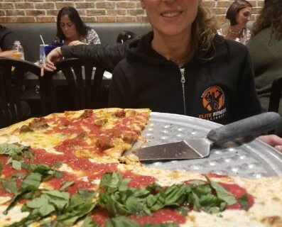 A woman eating pizza at a restaurant in East Brunswick, NJ